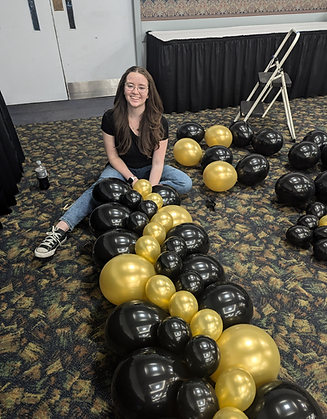 A picture of our creative owner who is building a flat balloon wall for the bottom of a stage