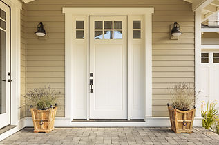 White front door with small square decorative windows and flower pots.jpg