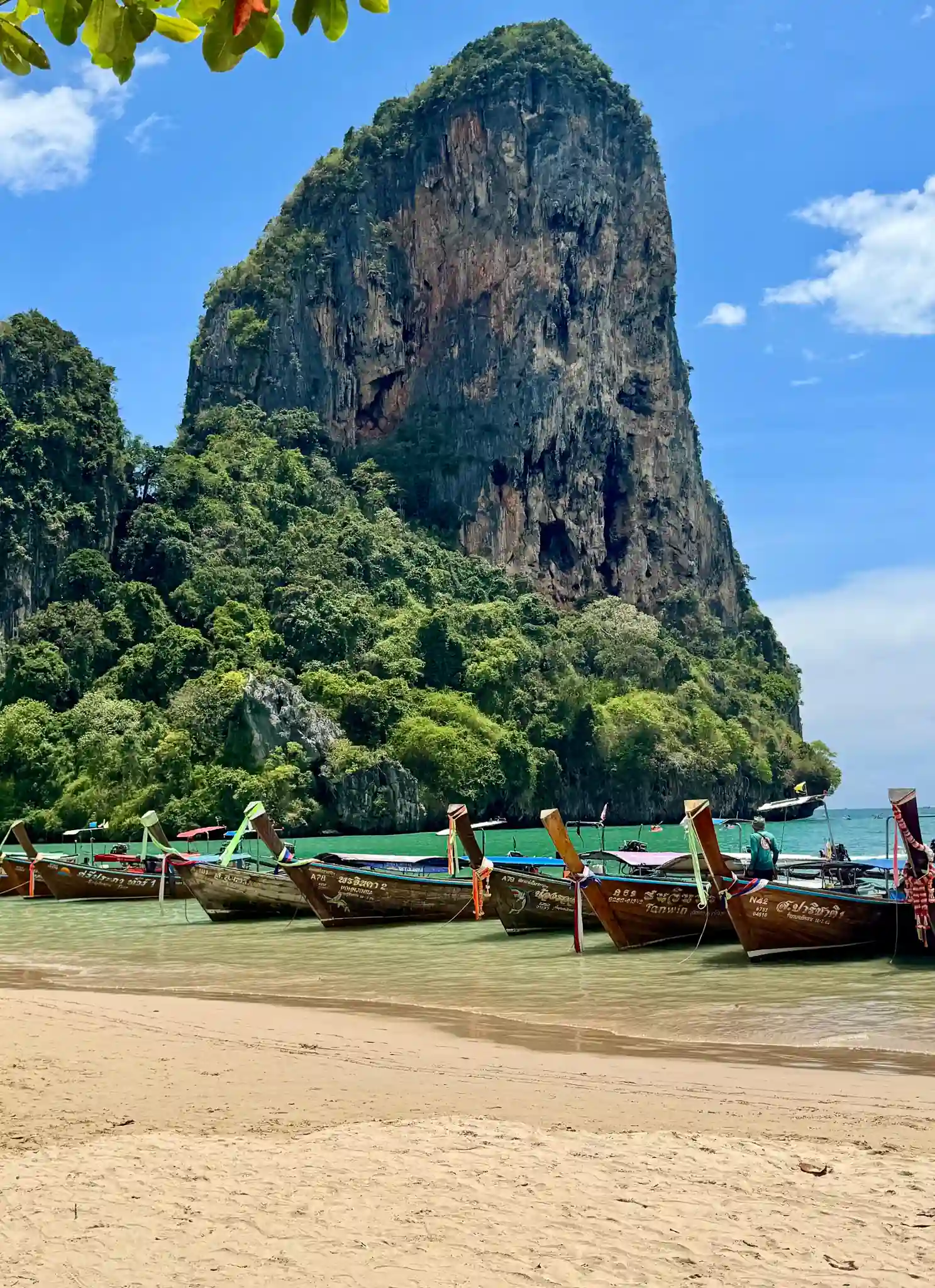 Plage sable bateaux long tail falaise Krabi Thaïlande