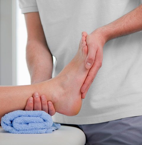 Mobile podiatrist holding and assessing a patient's ankle and foot over a blue towel