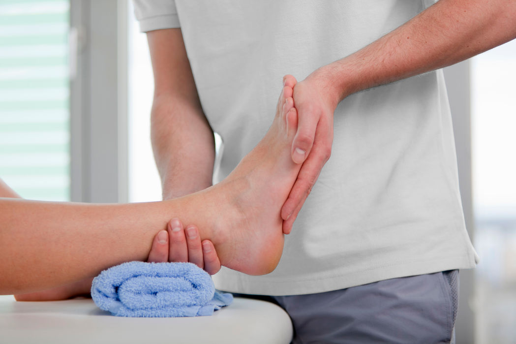 Physiotherapist extending a patients foot while they lay on a treatment bed