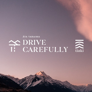 Pink Sunrise sky over mountain with the words Drive Carefully and the tiaki logo