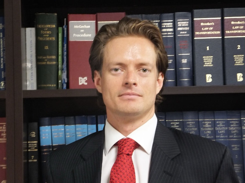Robert Samuel, experienced barrister, standing in front of a bookshelf filled with legal books.