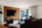 Luxurious living room with wooden wall, large TV, and stylish furnishings.