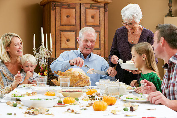 A multi-generational family gathered around a warmly set holiday dinner table, smiling and sharing a roasted turkey as the grandfather carves it, symbolizing the joyful passing down of traditions, values, and wealth without stress—fostering unity, gratitude, and open communication across generations.