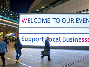 people walking in front of a JSG LED display in the city