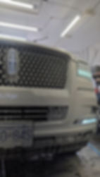 Front grille and logo of a white Lincoln SUV in a garage