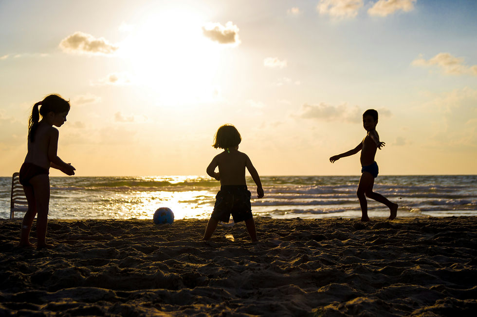 Silhouettes of three children playing soccer on the beach at sunset, demonstrating the peaceful and family-friendly atmosphere of evening beach visits
