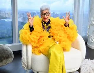 Woman in yellow ensemble gesturing with hands.