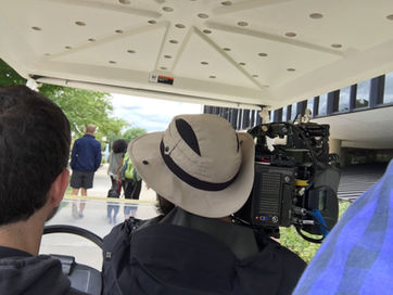 Cameraman in golf cart shooting students walking shot