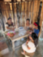 Group of people participating in a traditional Mayan cooking class. They are gathered around a table
