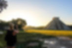 A women is taking a pictuere of the main structure "EL Castillo" at the archaeological site of Chichen Itza at sunrise.