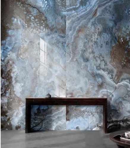 EstrellaSA Corfu sintered stone slab featuring a dramatic translucent onyx design with swirling layers of icy blue, smoky white, and contrasting deep amber-brown crystal formations