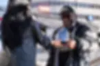 A woman in a leather jacket handing an African American man an award for Icons Among Us