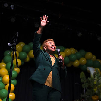 Mayor-Elect Barbara Lee at her election party in Oakland. She is standing on stage with green and yellow balloons behind her.