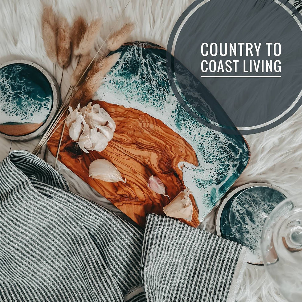 An ocean Resin olive wood cutting board with cloves of garlic and coasters beside it.
