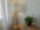 Eckbereich mit Holz-Stehlampe, Topfpflanze auf Beistelltisch und Vorhängen.
