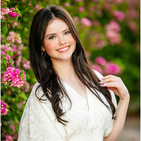 High school senior girl in a cream dress posing beside pink flowers. Photo by Jennifer Bowen Photography in Scottsdale AZ.
