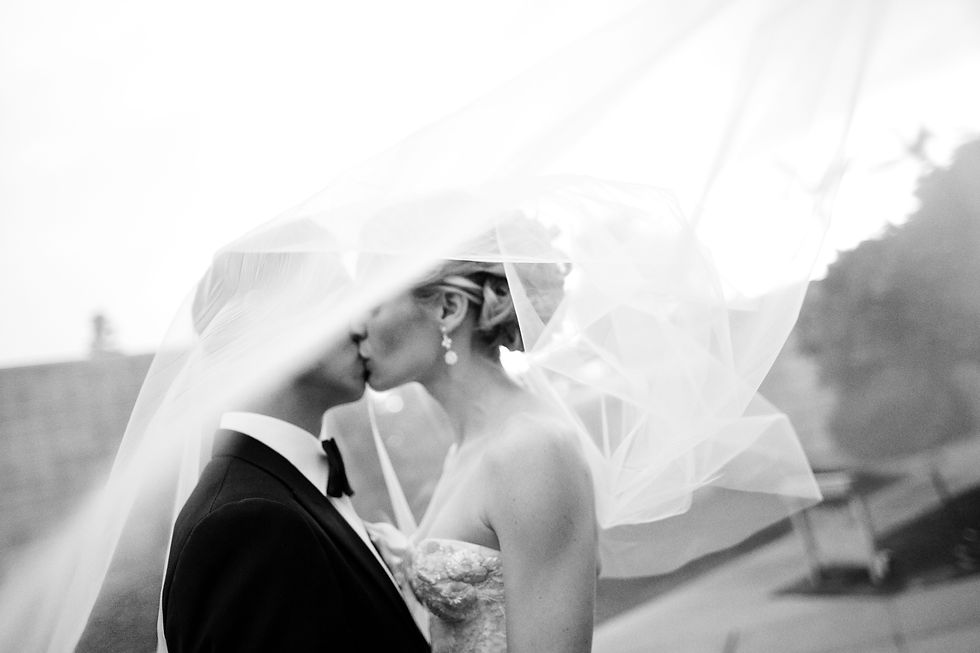 Black and white wedding photo of a couple kissing under her blowing veil. Circa 2011. Photo by Scottsdale Photographer Jennifer Bowen.