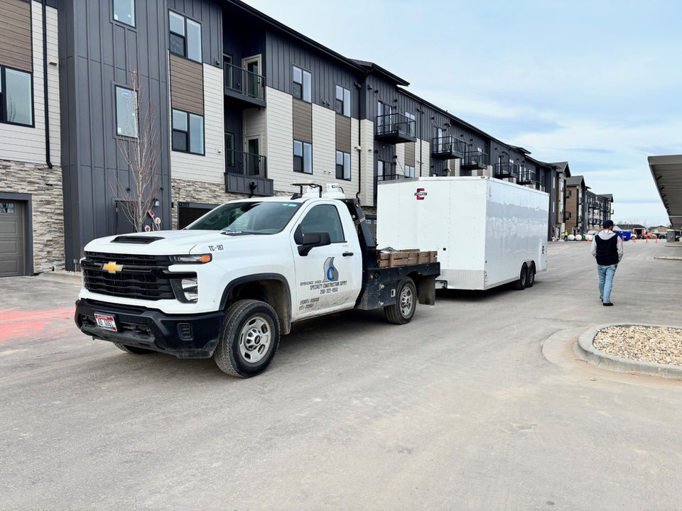 Service truck with wheelchair logo towing trailer at apartment complex