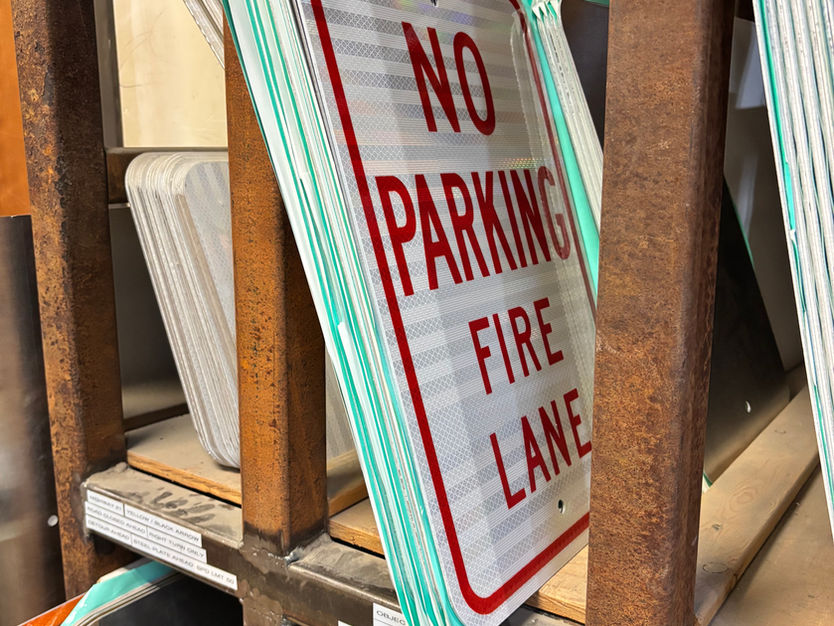 Stack of 'NO PARKING FIRE LANE' signs on a shelf