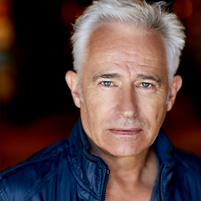 GERRY HUNGBAUER, actor with white short hair, bllue shiny shirt and light blue eyes, looking directly to the camera