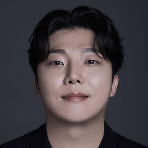 Korean tenor Beomjin Angelo Kim, y oung man with white skin , dark eyes and dark short hair, eom of it falling on the forehead, looking friendly into the camera.