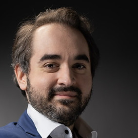 Tenor RAFAEL HELBIG-KOSTKA in a blue suit and an white open shirt, with dark hari and full beart and brown eyes simling to the camera - Concert at OPAL, Nationaltheater Mannheim