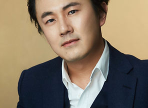 Headshot - Chinese Countertenor MEILI LI in a white shirt and a dark blue 3-part suit, with short hair and brown eyes, looking to the camera.
