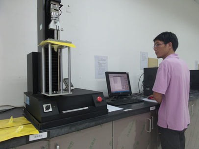 Adsure QC engineer conducting tensile strength test on plastic film using laboratory equipment.