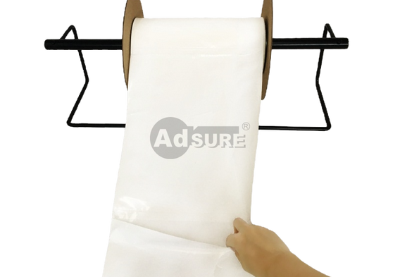 Hand pulling a recycled-content auto-mailer bag from a horizontal dispenser rack, demonstrating easy dispensing for packing stations.