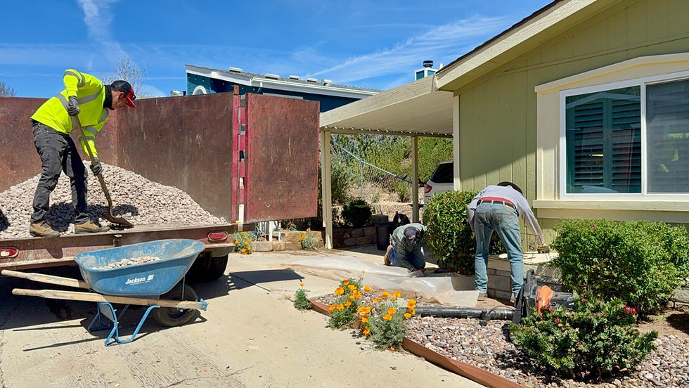 Workers install noncombustible rock beside an Acton home after removing combustible mulch from Zone 0.