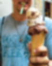 Person in a t-shirt holds a large triple-scoop ice cream cone. The shirt reads "Yosemite National Park." A spoon is in their mouth.