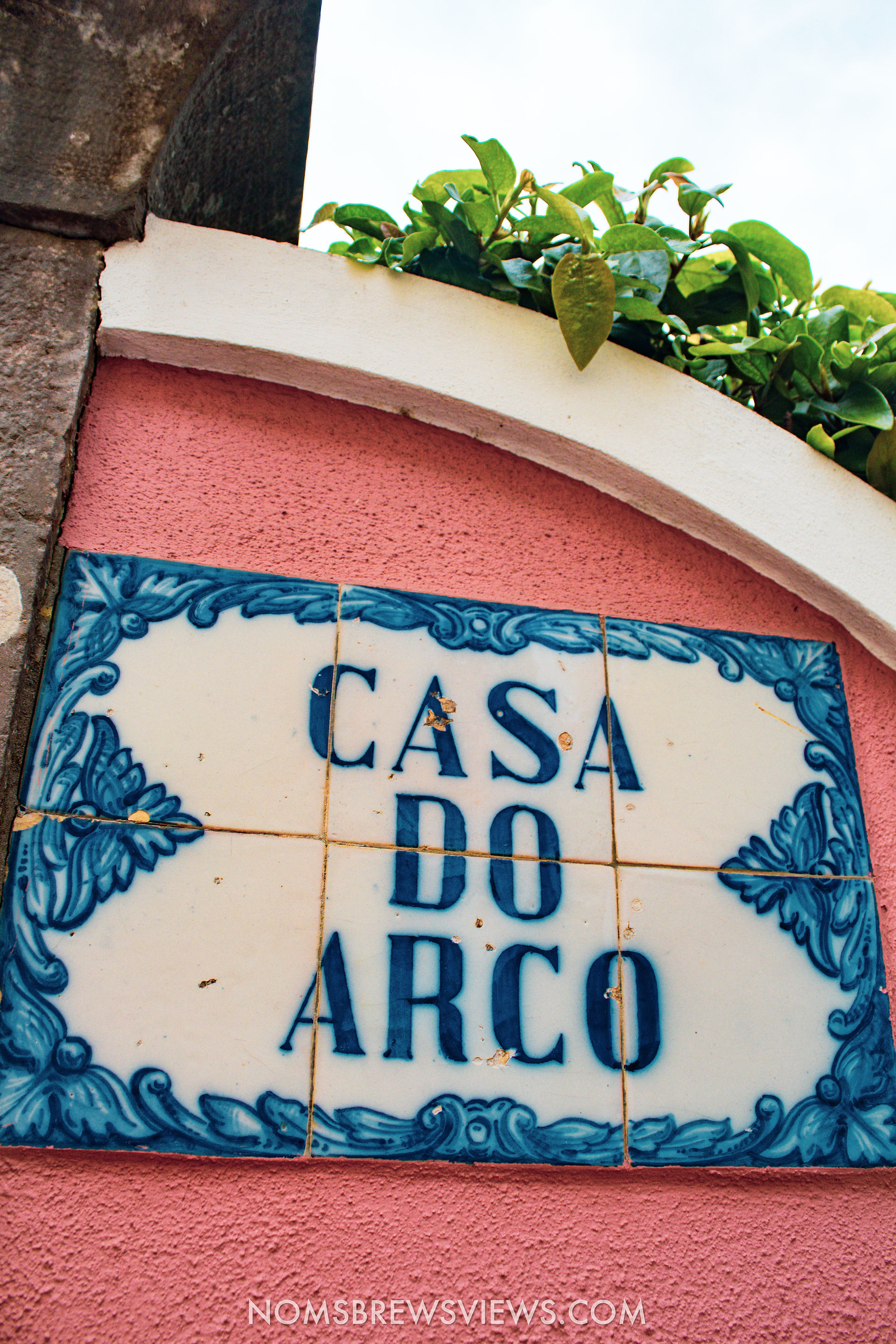 blue azulejos reading "casa do arco" on a pink building