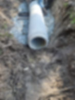 Concrete pipe laid on stone bedding within an excavation.