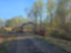 Excavator feeding brush into a tracked wood chipper during wooded-site clearing in Virginia.