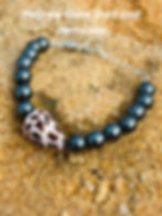 Hematite bracelet featuring the Hebrew Cone Shell & Gemstone Bracelet on sandy background.