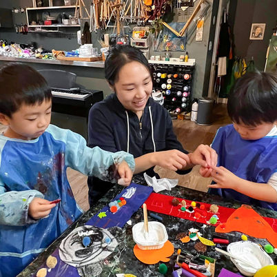 Mother smiles as two boys work on art projects.