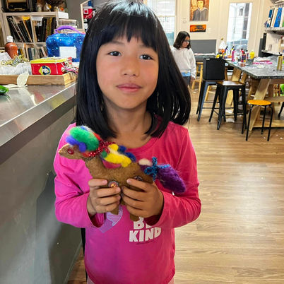 Student holds colorful felted and sewn horse art project.
