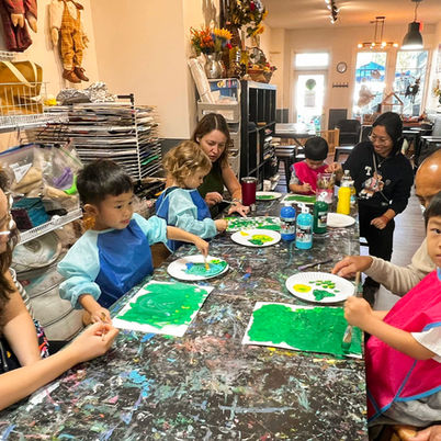 Children and parents gathered around table working on art projects.