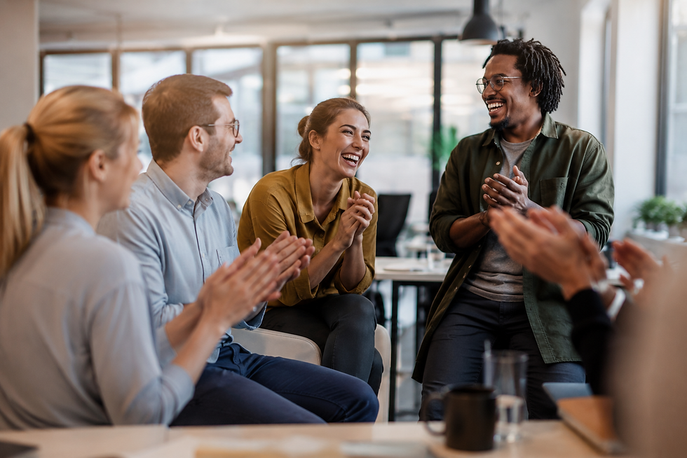 Eine Gruppe von Kolleginnen und Kollegen sitzt in einem hellen, modernen Arbeitsumfeld im Kreis zusammen. Die Teammitglieder lachen, applaudieren und begegnen sich offen und wertschätzend. Das authentische Foto symbolisiert psychologische Sicherheit, Stressbewältigung im Team, emotionale Resilienz sowie die positive Wirkung von Humor und zwischenmenschlicher Verbundenheit im Arbeitsalltag.