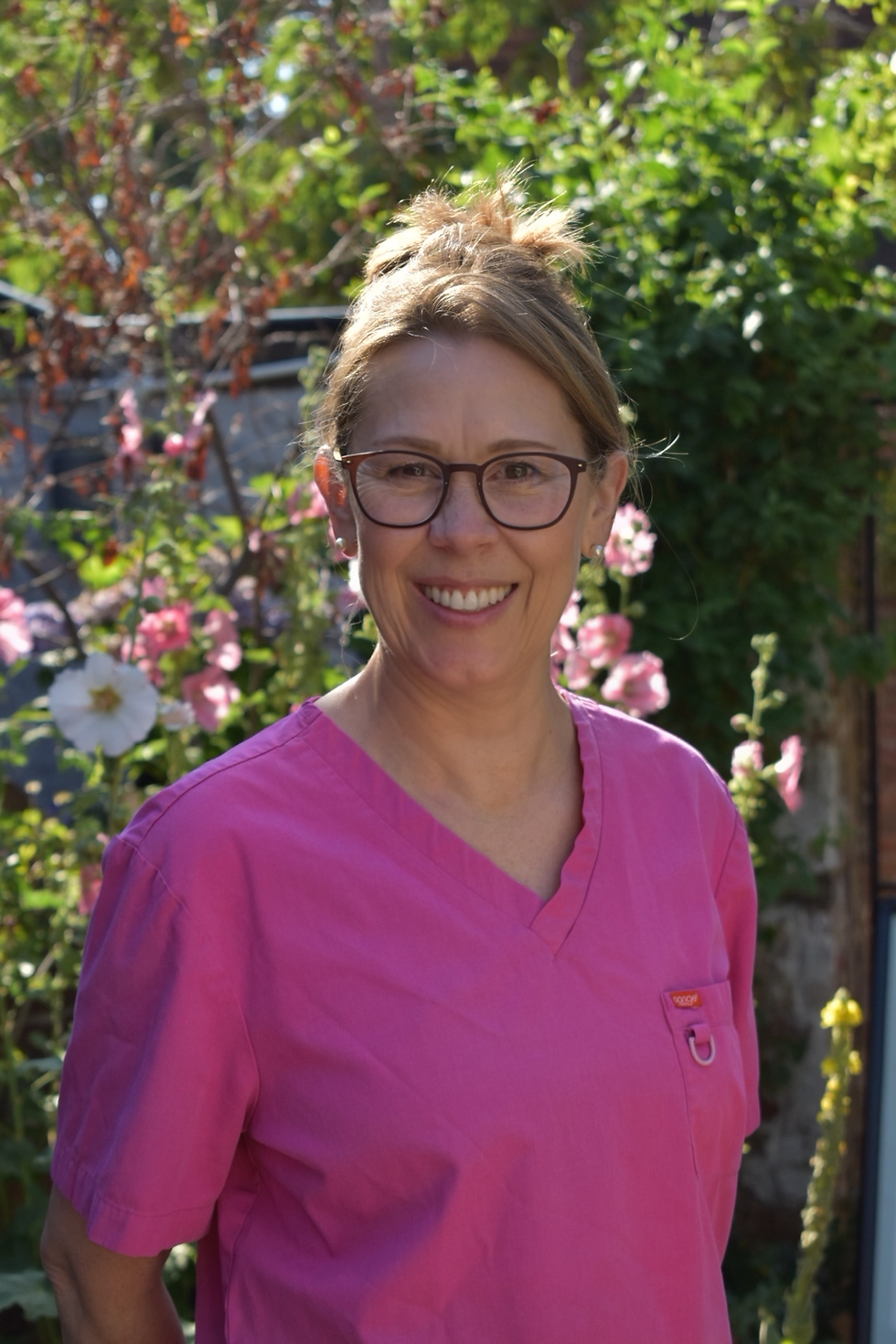 Andrea, a Hygienist in Farnham, smiling in pink scrubs.