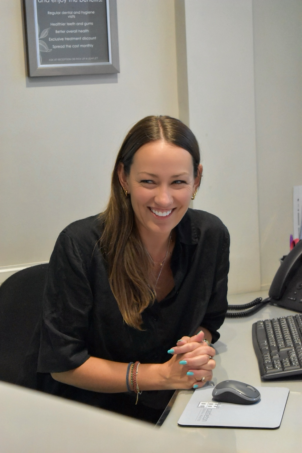Holly, a smiling practice manager, at her desk.