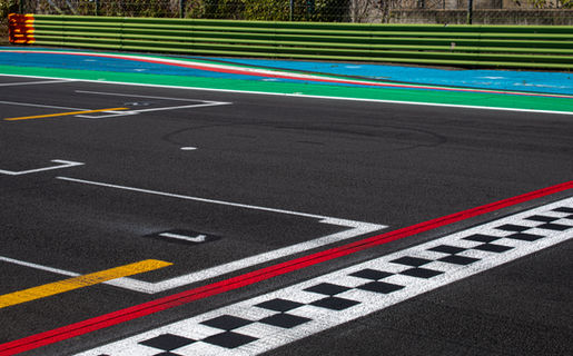 asphalt motorsport racetrack finish line with checkered pattern and striped curb