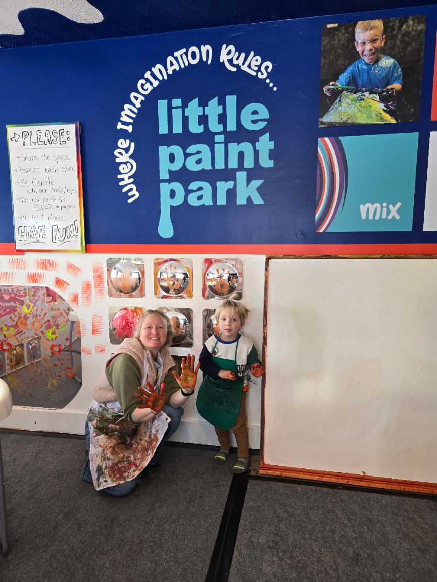 A toddler and his mom smile for a picture after having fun indoors at the Little Paint Park inside P
