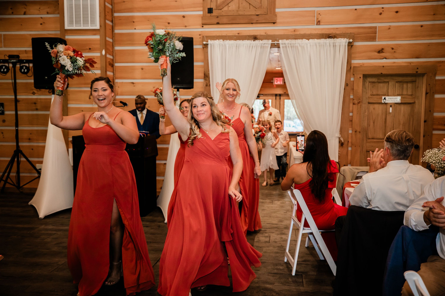 The wedding party making a joyful reception entrance with bouquets raised