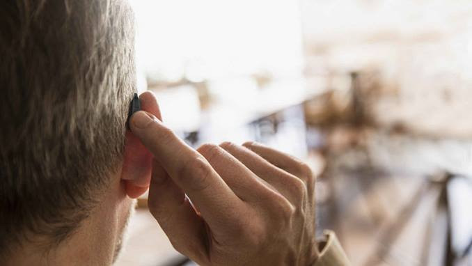 uomo che indossa un apparecchio acustico retroauricolare