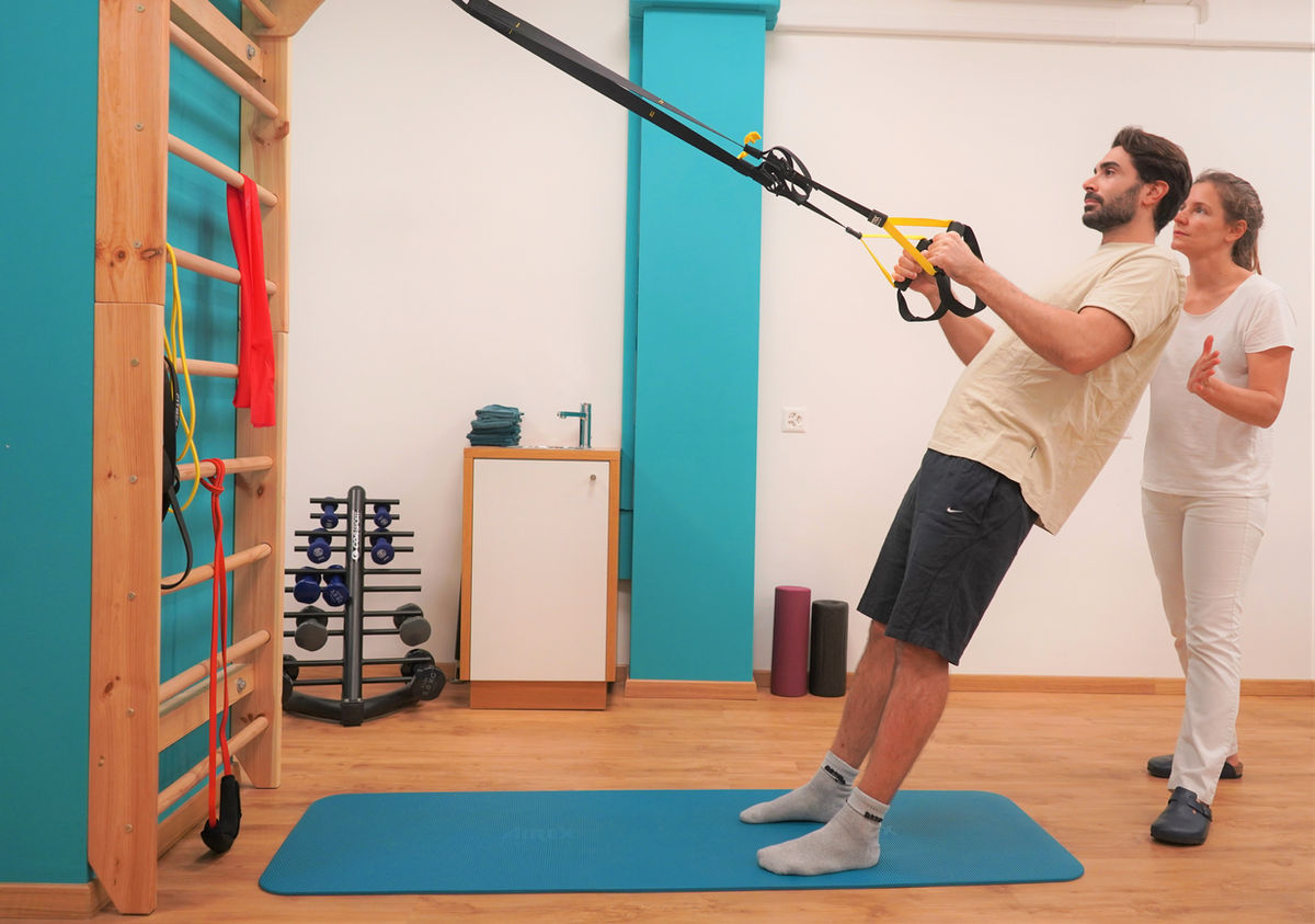 exercice de renforcement de l'épaule avec élastique ou haltère, accompagné par le physiothérapeute