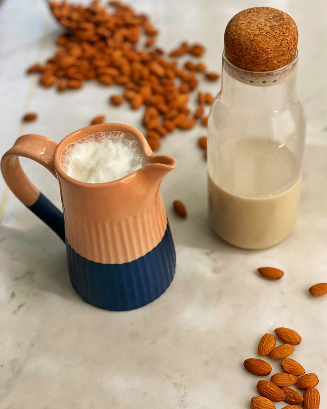 Fresh almond milk in a pitcher and bottle with almonds