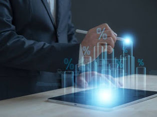 A person in a suit uses a stylus on a tablet. Holographic bar graphs with percentage signs rise from the screen, on a wooden table.